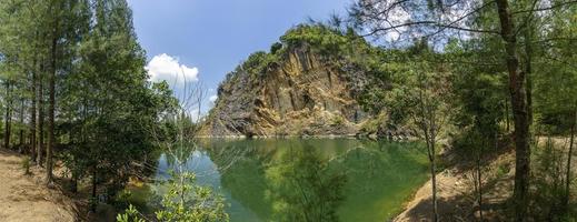 Emerald green pond Caused by digging limestone mines Blue sky and white clouds , Tons of wood covered photo