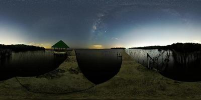 The Milky Way above a single tree and the bamboo landscape prevents the sea from breaking the coast. photo