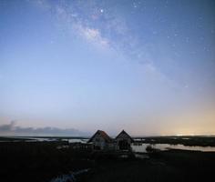 Milky Way early morning before sunrise , old abandoned house, red roof on open field photo