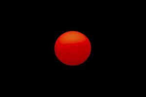 The evening or morning sun can be seen with the naked eye. The sun is red because of the dust and atmosphere. photo