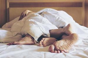 Couple on white bed in hotel room focus at feet photo