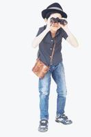 7 years old Asian traveler boy is standing and using binoculars isolated on white background photo