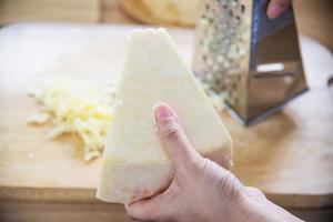 mujer preparando queso para cocinar usando rallador de queso en la cocina - gente haciendo comida con concepto de queso foto