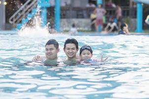 Father and his two son play in clear water swimming pool - happy family play time concept photo