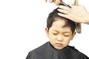 un niño se corta el pelo con un peluquero aislado sobre fondo blanco foto