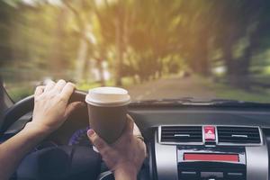 dama conduciendo un auto mientras sostiene una taza de café foto