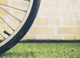 Bicycle wheel over green vintage grass and brick wall background photo
