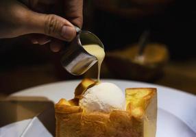 People pouring milk on ice cream bread toast - people with toast dessert sweet eating concept photo