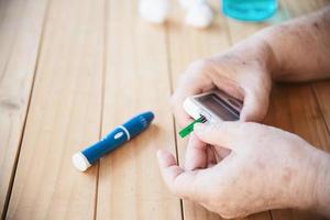 Old lady is testing blood sugar level using blood sugar test kid set - people with medical equipment concept photo