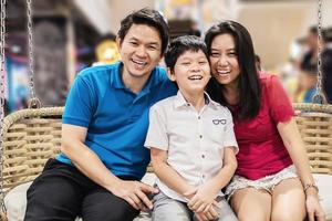 Happy smile family father mother and son sitting on public swing bamboo weaved chair - happy family life concept photo