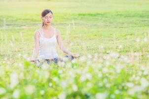 señorita haciendo ejercicio de yoga en el campo verde al aire libre mostrando calma pacífica en la mente de meditación - la gente practica yoga para la meditación y el concepto de ejercicio foto