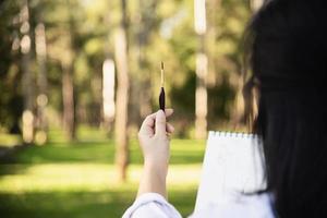 Relax woman painting water colour art work in green garden forest nature - people with creative art in nature stress reduction and meditation concept photo