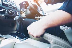 Closeup of man hand pulls car hand brake while driving car - car safe drive concept photo