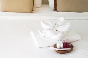 juego de toallas de hotel con cepillo de dientes y pasta de dientes en cama blanca foto