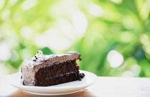 Chocolate cake on table with green garden background - relax with bakery and nature concept photo