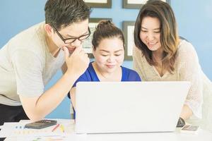 Two women and one man are happily looking at computer in modern office photo