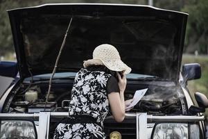 mujer asiática que llama al reparador o al personal de seguros para solucionar un problema de motor de camión en una carretera local - personas con concepto de transporte de problemas de camión foto