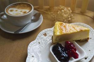tarta de queso con una taza de café caliente sobre una mesa de madera foto