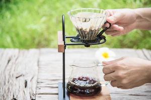 hombre haciendo goteo de café recién hecho en una cafetería antigua con fondo verde de la naturaleza - gente con café recién hecho en el concepto de naturaleza foto