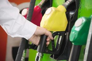 hombre poniendo gasolina en su coche en una gasolinera de bomba foto