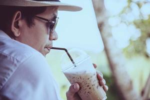 Casual Asian man drink ice coffee happily in nature - people with coffee in nature concept photo