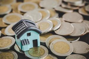 modelo de casa y pilas de monedas de dinero en el fondo de la mesa borrosa. planes de ahorro para vivienda, préstamo, inversión, hipoteca, finanzas y banca sobre el concepto de casa. foto