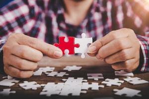 Hands holding jigsaw puzzles piece on wooden table background, success business, solution strategy, teamwork partnership concept photo