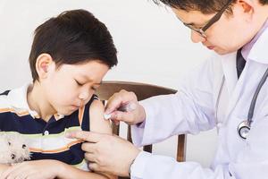 Sick Asian boy being treated by male doctor over white background photo