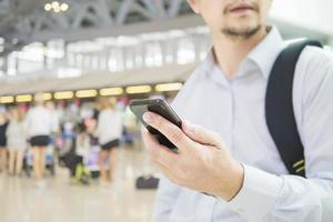 viajero de negocios usando teléfono móvil durante su viaje en la terminal del aeropuerto foto