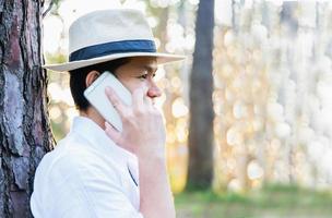 Asian man with mobile phone in forest tree nature - people in spring nature and technology concept photo