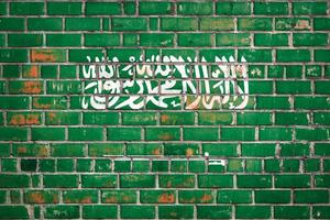 National  flag of the Saudi Arabia on a grunge brick background. photo