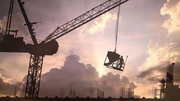 silhouette de travailleurs travaillant sur un chantier de construction, les travailleurs de la construction travaillent en vue de la liaison des barres d'armature et des travaux de béton avec des nuages en accéléré qui se déplacent.