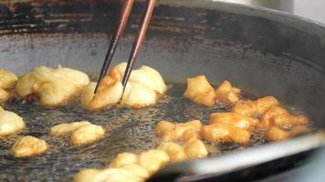 B Roll slow-motion deep-fried dough stick or patongko being fried in a pan with boiling oil, Thailand street food breakfast favorite among tourists