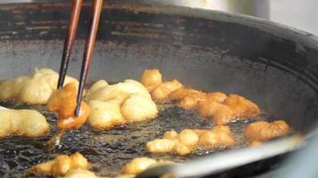 b roll 4k bastoncino di pasta fritta al rallentatore o patongko fritto in una padella con olio bollente, thailandia street food colazione preferita dai turisti video