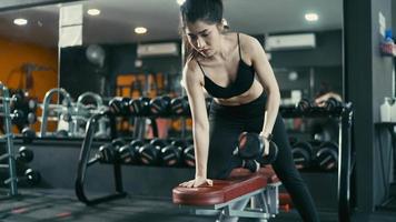 Young fit woman exercising with dumbbels in the gym video