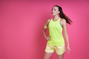 Beautiful woman in sports clothing wearing captain band and standing against pink background photo