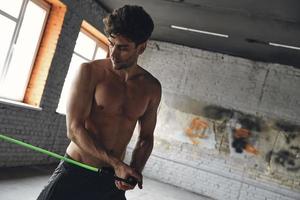 Handsome young man exercising with elastic resistance band in gym photo