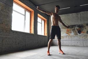 Full length of confident young man exercising with resistance band in gym photo