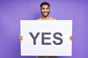 hombre africano feliz sosteniendo una pancarta mientras se enfrenta a un fondo morado foto