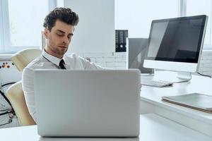 Handsome young man using computer while sitting at his working place in office photo