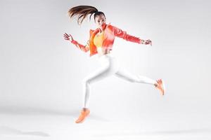 Hermosa mujer joven en ropa deportiva corriendo contra el fondo blanco. foto