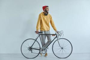 Happy young African man standing near his bicycle against the wall photo