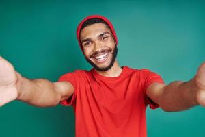 hombre africano feliz estirando las manos mientras está de pie contra el fondo verde foto