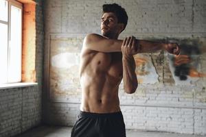 Handsome young man warming up before training in gym photo