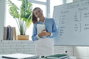 Beautiful young woman standing near the whiteboard at the classroom photo