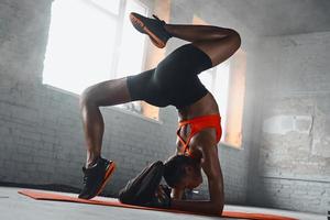 hermosa joven africana haciendo el pino se divide en el gimnasio foto