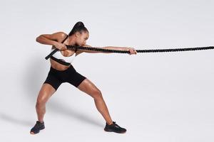 Concentrated young African woman pulling a rope against white background photo