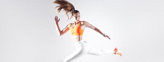 mujer joven confiada en ropa deportiva corriendo contra el fondo blanco foto