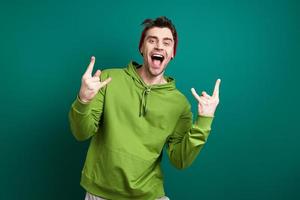 Excited young man gesturing while standing against green background photo