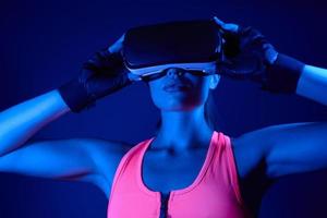 Confident young woman in sports clothing wearing virtual reality glasses photo